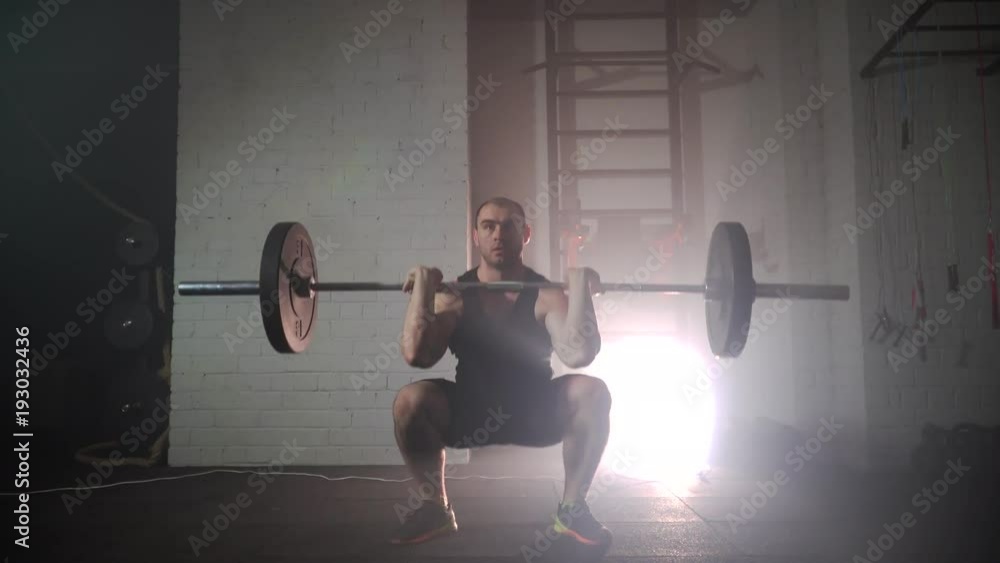 the athlete crouches with a barbell in the gym the athlete crouches with a barbell in the gym