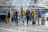 Full length portrait of group of tourist chasing each other at the airport. Their faces are joyous