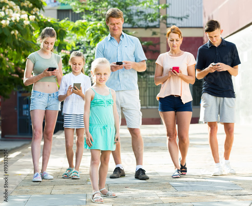 Portrait of modern large family standing with their mobile phones outdoors