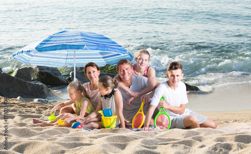 Large happy family of six people together on beach