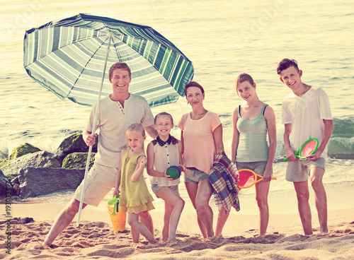 Large smiling family standing together on beach on summer day