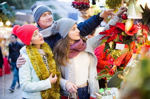 cheerful parents with teenage girl at counter with Poinsettia and floral decorations