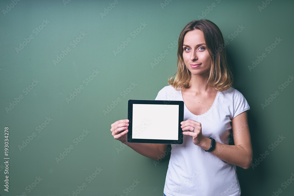 Digital technology. Young pretty woman holding tablet computer with copy space on the screen against green wall. Digital technology. Young pretty woman holding tablet computer with copy space on the screen against green wall.