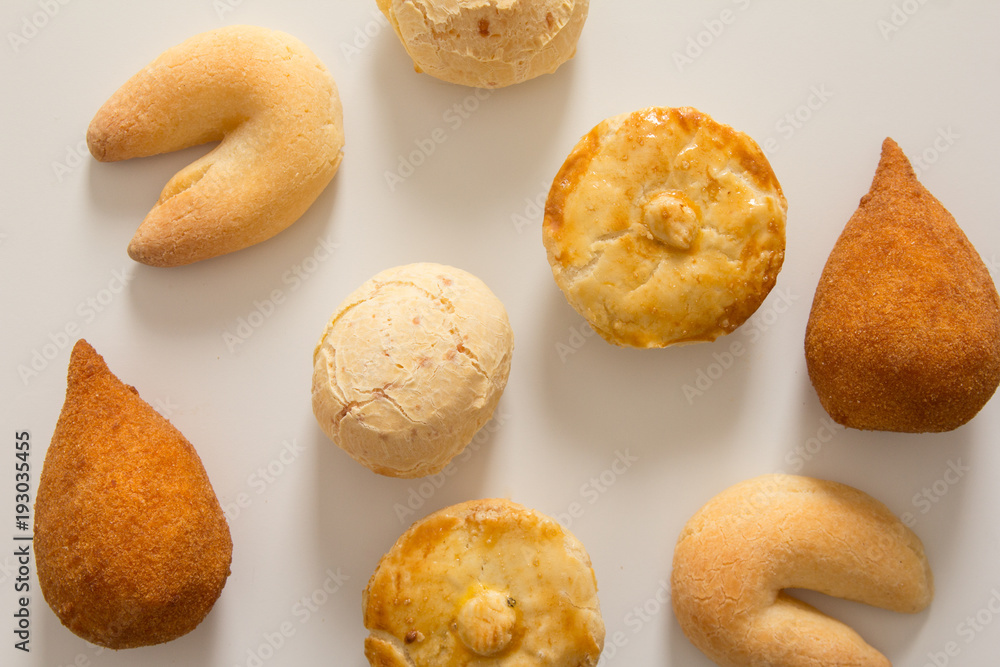 Assorted snacks: Pao de Queijo, Chipa, Coxinha and Empada. Group of typical food from Brazil. Top View, flat lay design on white background.