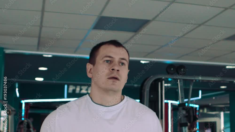 Young happy handsome man with tattoo in fitness club. Cardio workout, running on treadmill. Healthy lifestyle, guy training in gym. Flare effect Young happy handsome man with tattoo in fitness club. Cardio workout, running on treadmill. Healthy lifestyle, guy training in gym. Flare effect