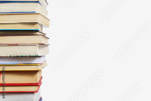 Stack of different books on a table against a white wall background