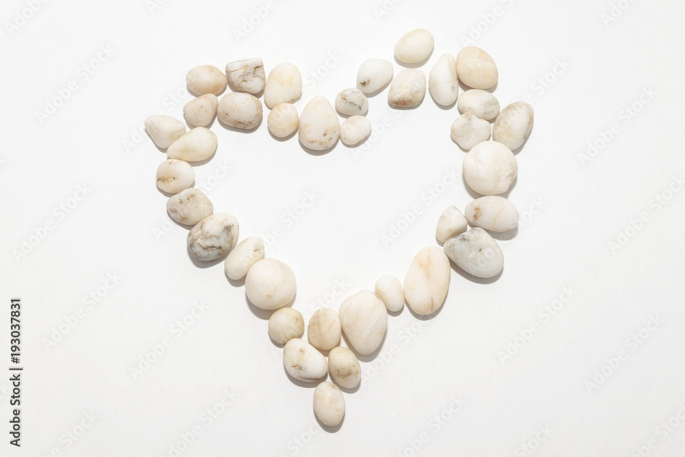 Heart on a white background lined with small white decorative stones, concept romantic, decor, art Heart on a white background lined with small white decorative stones, concept romantic, decor, art
