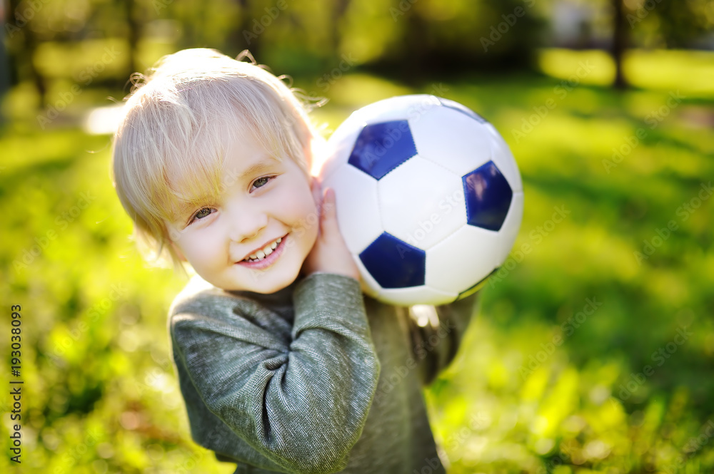 Little boy having fun playing a soccer game on sunny summer day Little boy having fun playing a soccer game on sunny summer day