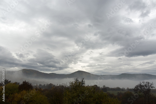 nature  atmosphere  wildlife concept. the sky like a sea all covered by waves  puffy grey clouds  that promise the rain and cold weather  they are floating under valley at the foot of mountain