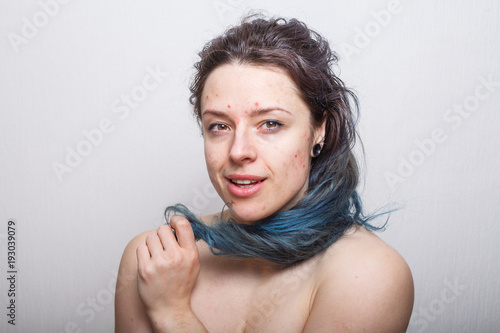 Young woman rolling her colorful but damaged messy hair on her finger. Absolutely no retouching. photo