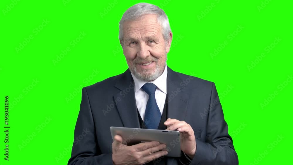 Cheerful senior entrepreneur with pc tablet. Happy elderly businessman typing a message on digital tablet, chroma key background. Cheerful senior entrepreneur with pc tablet. Happy elderly businessman typing a message on digital tablet, chroma key background.