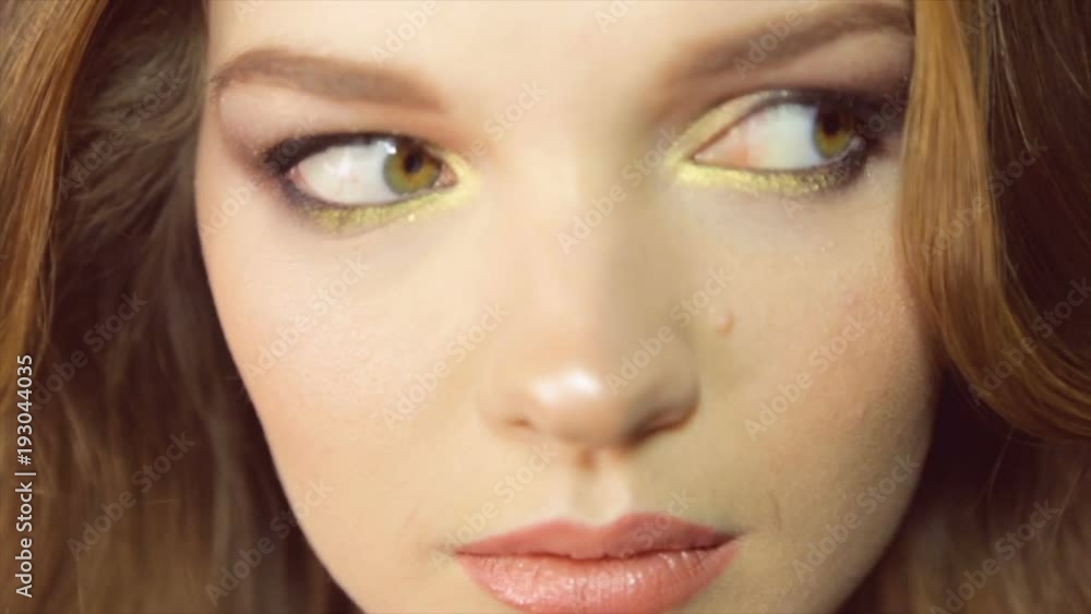 Model poses on camera. Portrait of girl close-up with painted eyes Model poses on camera. Portrait of girl close-up with painted eyes