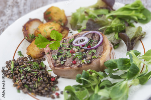 Beef tournedos and roquefort sauce with roasted potatoes and salad ans lentils on awhite plate grey background photo