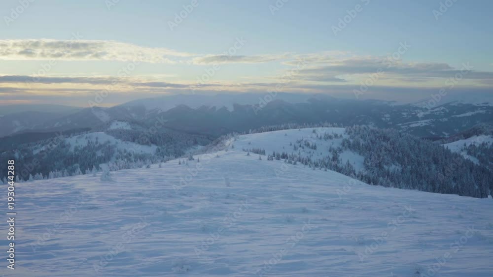 Frozen and snow covered landscape and trees on mountains during winter sunset Frozen and snow covered landscape and trees on mountains during winter sunset