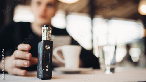 Using electronic cigarette to smoke in public places.Smoke restriction,smoking ban.Using vaping device with flavoured liquid.E-juice vaping new technology.Give up tobacco.Smoking habit,nicotine addict photo