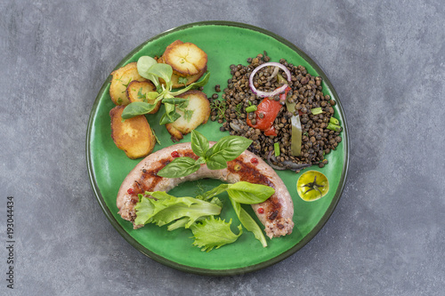 France Grilled Toulouse sausage with roasted potatoaes and salad and lentils on grey background
