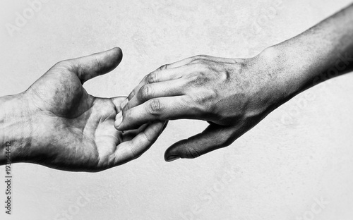 Emotional, black and white photo of two hands at the moment of farewell. The concept of breaking relations.