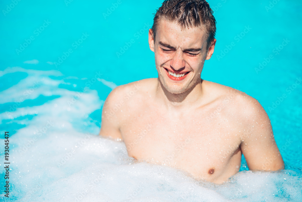 Young man rubbing eyes in swimming pool.Summer activity.Contact lens