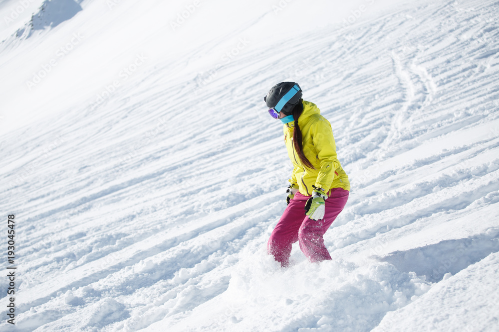 Picture of athlete brunette in helmet and mask, snowboarding from snowy mountain slope Picture of athlete brunette in helmet and mask, snowboarding from snowy mountain slope