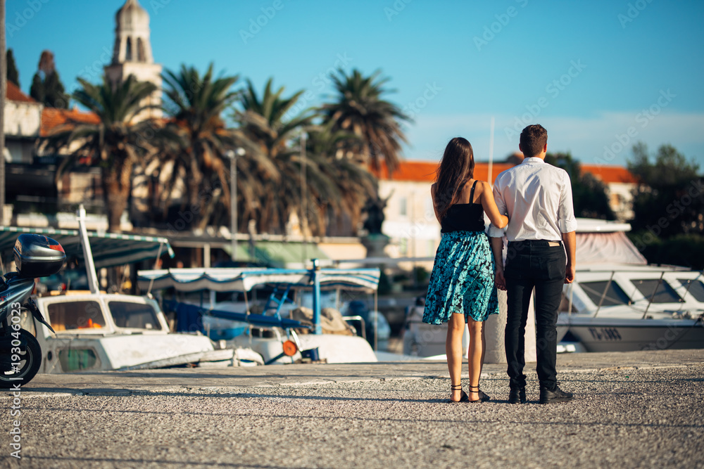 Young couple enjoying vacation time.Boyfriend and girlfriend having a romantic walk along the coast in a seaside town.Romantic weekend at he coastal city,holiday at the seaside.Relaxing walk at sunset