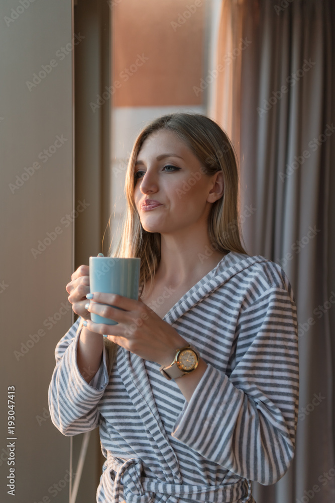 young woman enjoying evening coffee by the window young woman enjoying evening coffee by the window