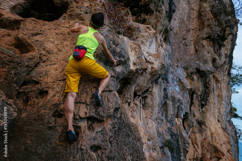 female rock climber climbing on seaside cliff