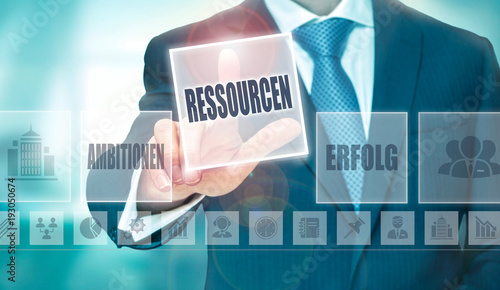 A businessman pressing a Resources "Ressourcen" button in German on a futuristic computer display