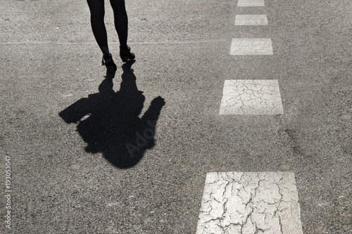 Shadow of a woman from waist down crossing the road photo