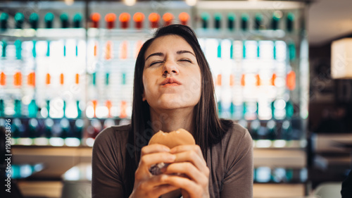 Photography Young woman eating fatty hamburger