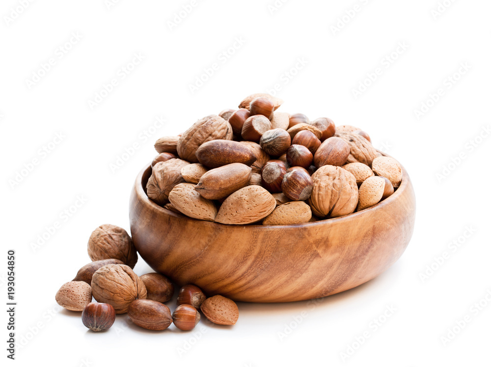 Various nuts in wooden bowl isolated on white Various nuts in wooden bowl isolated on white