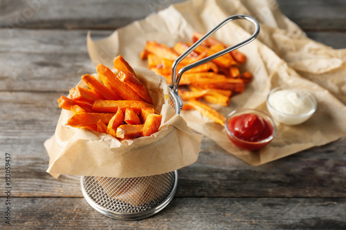 Deep fry basket with sweet potato fries on wooden table