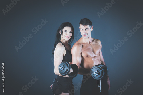 Athletic man and woman with dumb-bells. Personal fitness instructor. Personal training. Weight training. Workout.