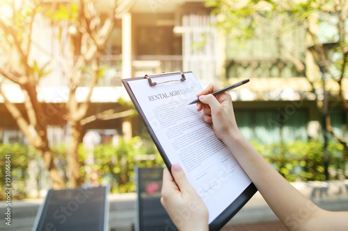close up portrait of woman hands signing rental agreement on background of leasing office apartments. girl travel and rent short term condo in america. concept of traveler looking for place to live