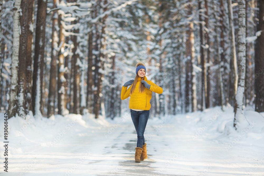 Young smiling woman in a bright clothes stands on a road in a winter forest