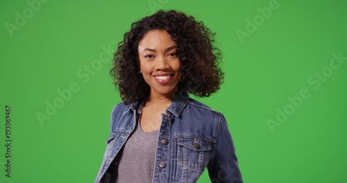 Portrait of happy black woman in jean jacket posing playfully on green screen. Close up of stylish African American Millennial girl smiling and laughing on greenscreen for keying or compositing. 4k