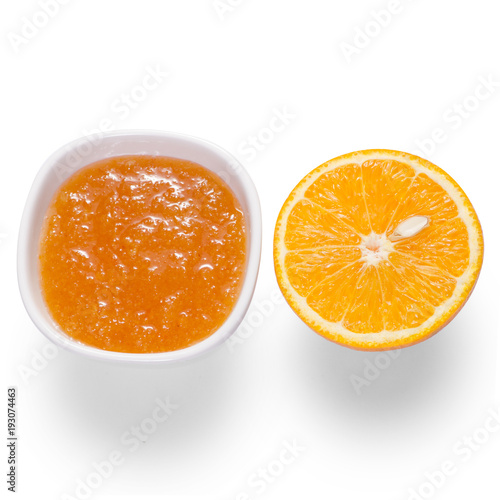 Orange jam in a white bowl with orange fruit