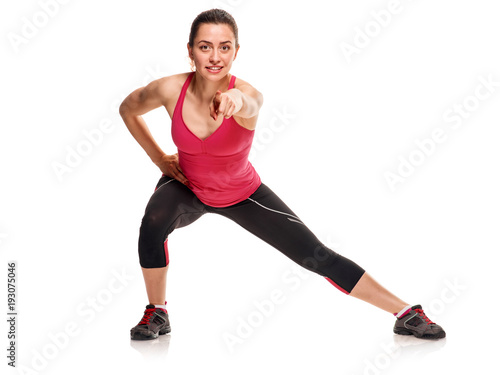 Sporty woman exercising. Sporty young woman exercising on white background and pointing on camera