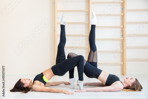 two beautiful girls on floor stretch their legs in stretching up