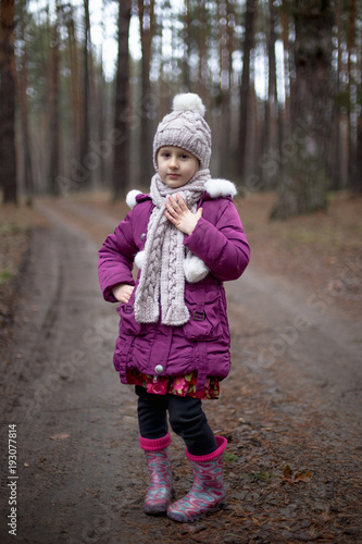 Little cute girl posing on the road in the pine forest in autumn time