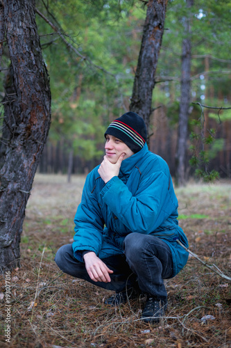 A rural guy posing in a pine forest in the autumn time.