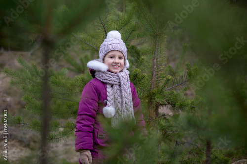 A cute little girl in a pine forest in the autumn time.