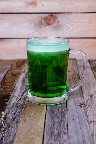 Single mug of green beer on wooden background