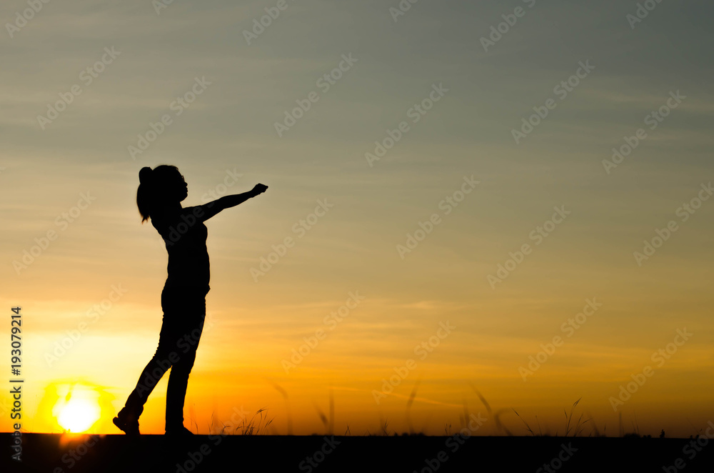 Woman silhouette is standing, raise one's hand for exercise, on evening .