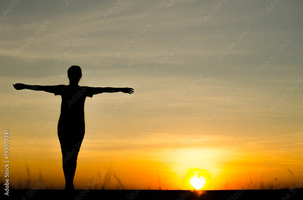 Fototapeta premium Woman silhouette is standing, raise one's hand for exercise, on evening .