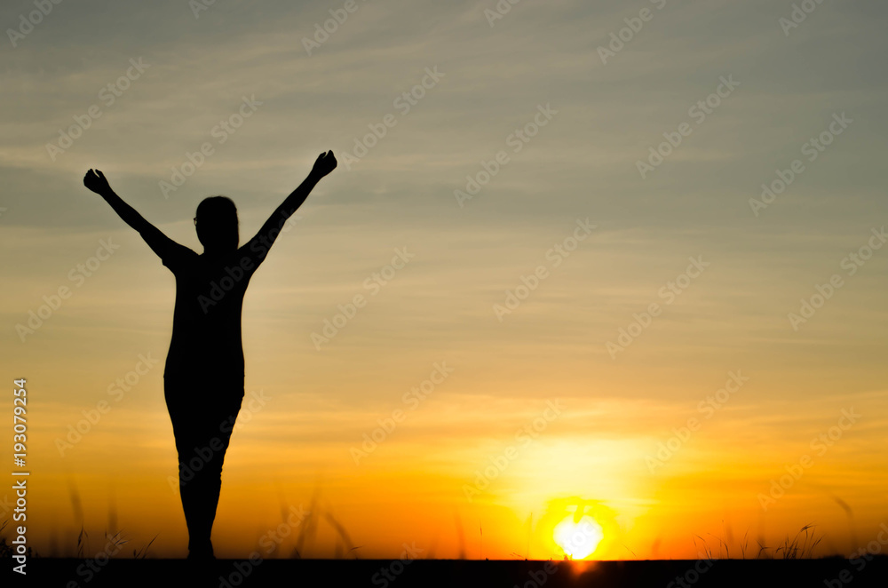 Woman silhouette is standing, raise one's hand for exercise, on evening .