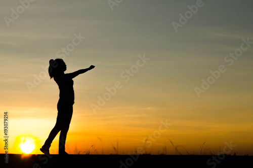 Woman silhouette is standing, raise one's hand for exercise, on evening .