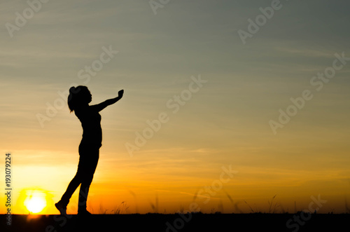 Woman silhouette is standing, raise one's hand for exercise, on evening .