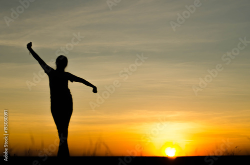 Fototapeta Naklejka Na Ścianę i Meble -  Woman silhouette is standing, raise one's hand for exercise, on evening .