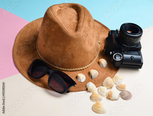 The concept of a resort on the beach. Felt hat  sunglasses  vintage film camera  seashells on a colored paper background..