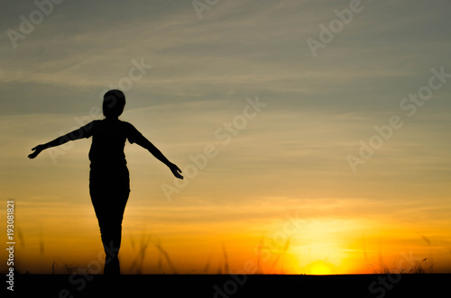 Woman silhouette is standing  raise one s hand for exercise  on evening .